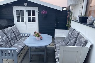 Überdachte Terrasse mit Lounge-Möbeln und Gartenhaus